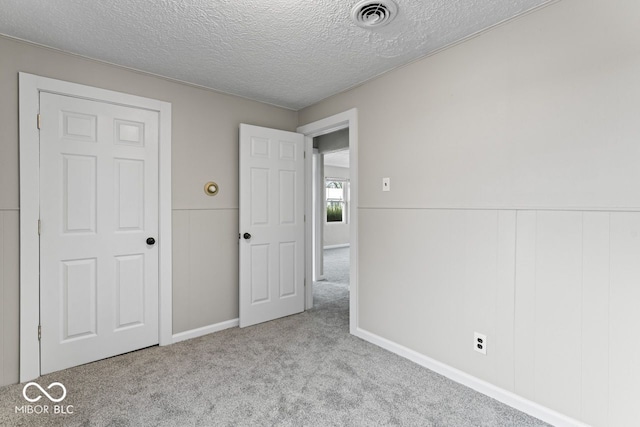 unfurnished bedroom with light carpet and a textured ceiling