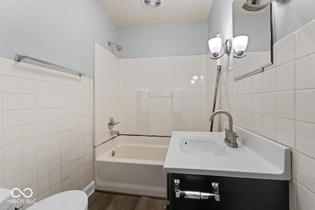 full bathroom with vanity, a textured ceiling, hardwood / wood-style flooring, tile walls, and toilet