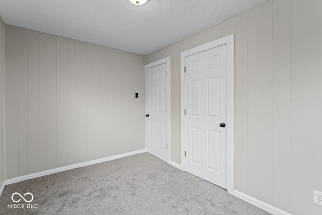 unfurnished bedroom featuring wood walls and carpet floors