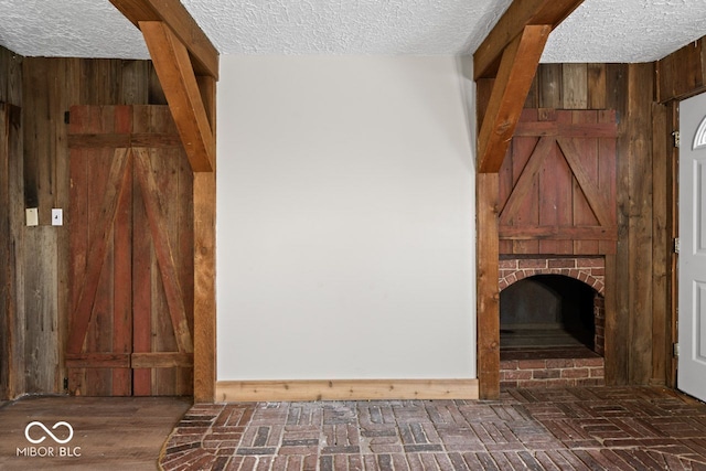 unfurnished living room with wooden walls, a textured ceiling, and a brick fireplace