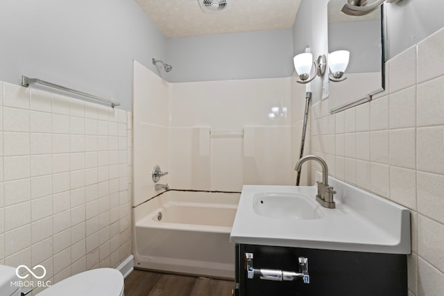 full bathroom with vanity, a textured ceiling, wood-type flooring, tile walls, and toilet