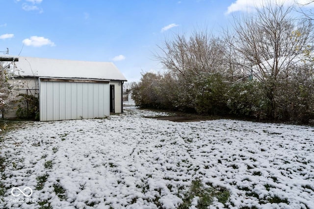 snowy yard featuring an outbuilding and a garage