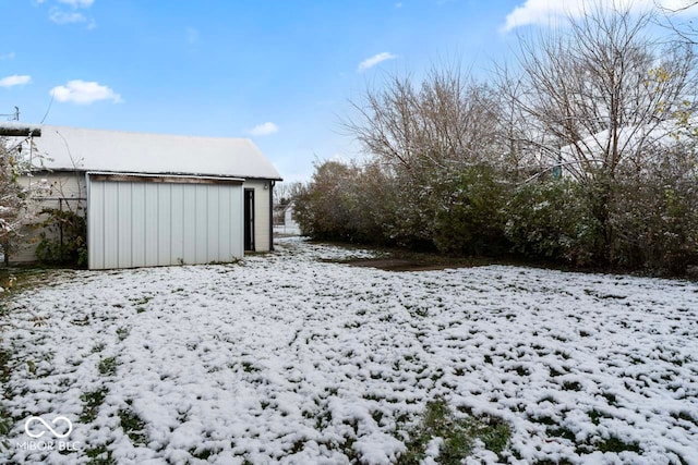 yard covered in snow with an outbuilding and a garage