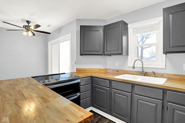 kitchen with ceiling fan, sink, electric range, gray cabinets, and butcher block countertops