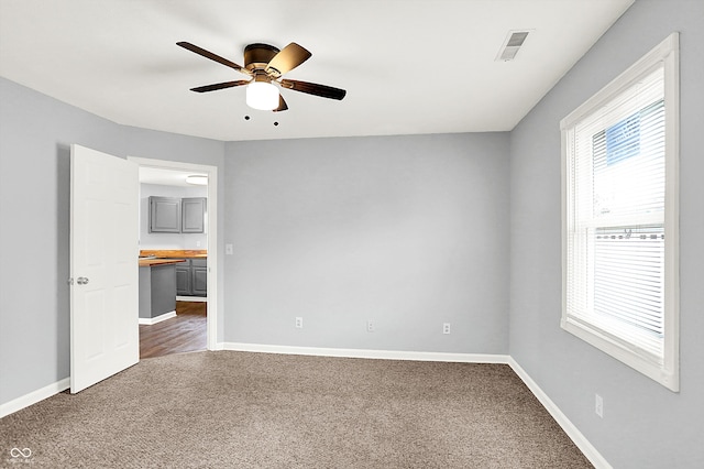 carpeted spare room with ceiling fan and a healthy amount of sunlight