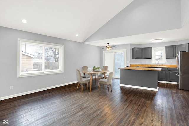 dining area featuring ceiling fan, sink, high vaulted ceiling, and dark hardwood / wood-style floors