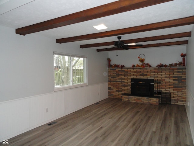 unfurnished living room featuring beamed ceiling, ceiling fan, wood-type flooring, and a fireplace