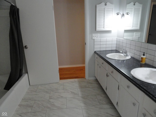 bathroom with tasteful backsplash, shower / bath combo with shower curtain, and vanity