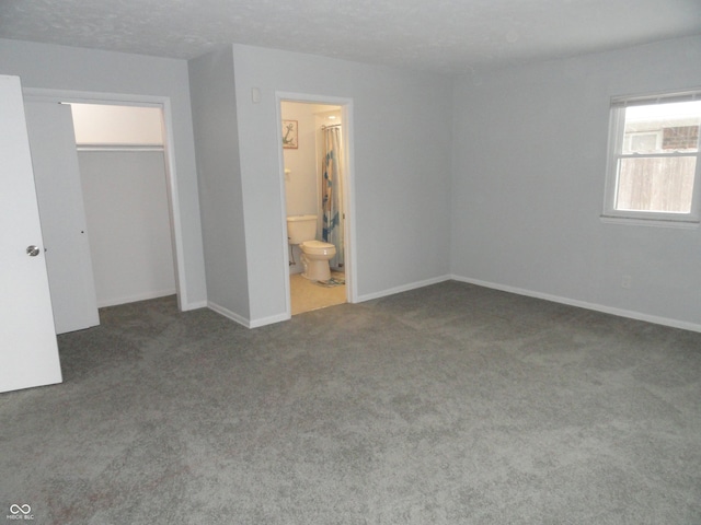 unfurnished bedroom featuring ensuite bath, a closet, and carpet floors