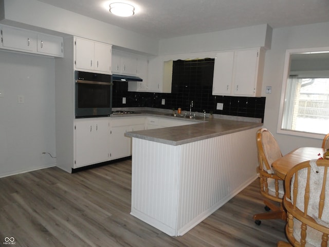 kitchen featuring kitchen peninsula, dark wood-type flooring, sink, oven, and white cabinetry