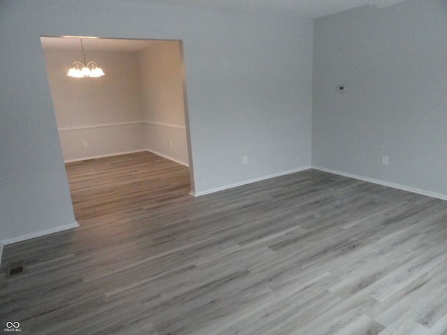 unfurnished room with hardwood / wood-style floors and an inviting chandelier