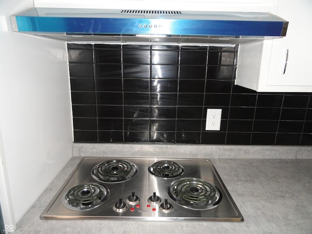 interior details with white cabinets, wall chimney range hood, and stainless steel electric stovetop