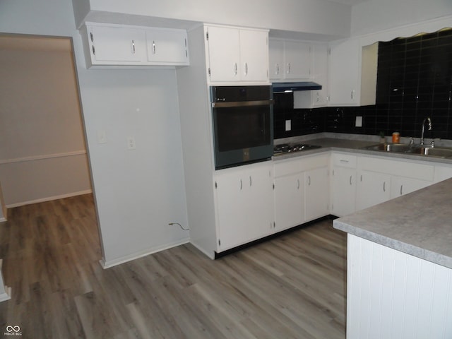 kitchen with dark hardwood / wood-style flooring, backsplash, sink, white cabinets, and oven