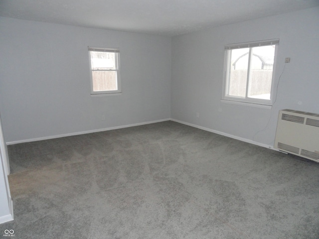 spare room featuring carpet flooring, heating unit, and radiator