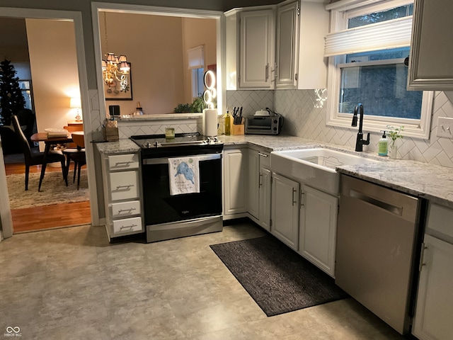 kitchen with backsplash, light stone countertops, sink, and appliances with stainless steel finishes