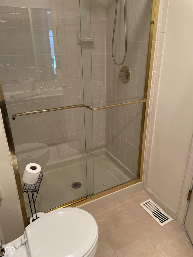 bathroom featuring toilet, tile patterned floors, and walk in shower