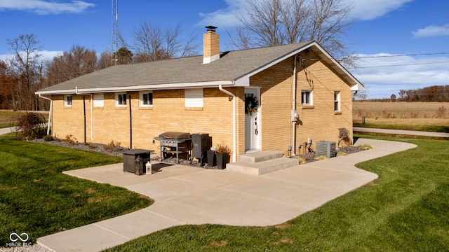 back of house with central air condition unit, a patio area, and a lawn