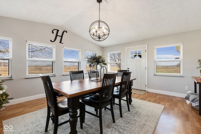 dining space featuring a chandelier, a healthy amount of sunlight, lofted ceiling, and light hardwood / wood-style floors