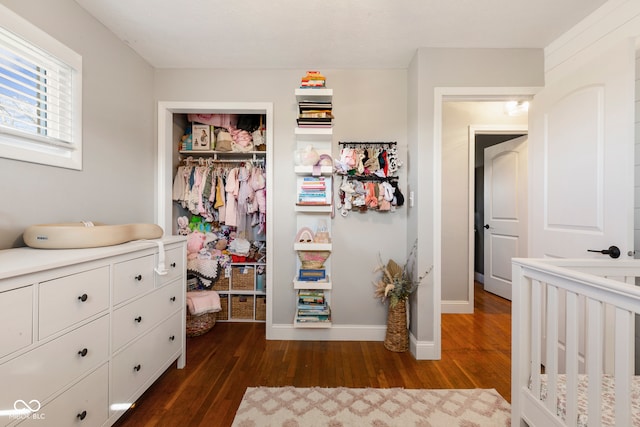 bedroom featuring a crib, dark wood-type flooring, and a closet