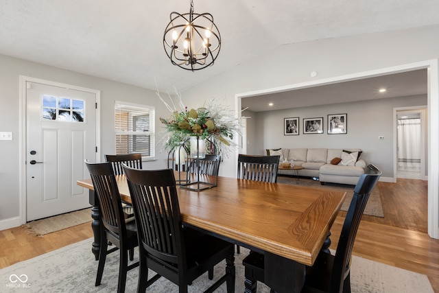 dining room featuring a chandelier, light hardwood / wood-style flooring, and vaulted ceiling