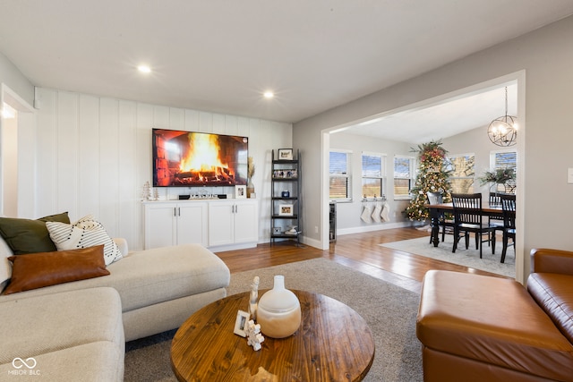 living room with hardwood / wood-style floors, a notable chandelier, and lofted ceiling