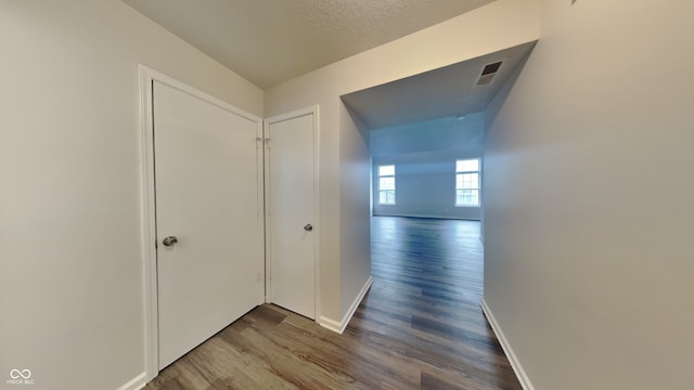 hall with a textured ceiling and hardwood / wood-style flooring