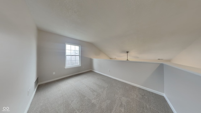 additional living space featuring carpet floors and vaulted ceiling