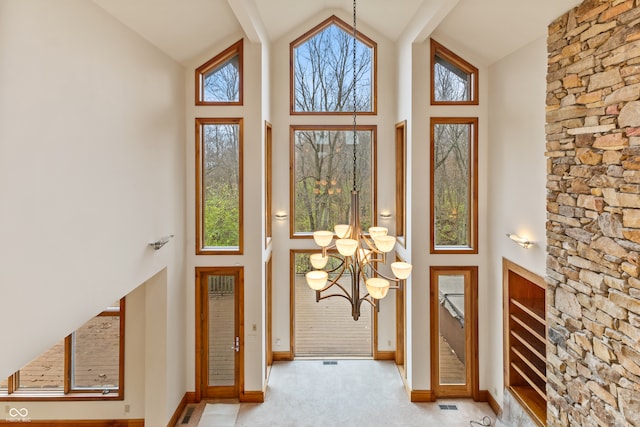 doorway with light carpet, high vaulted ceiling, and a chandelier