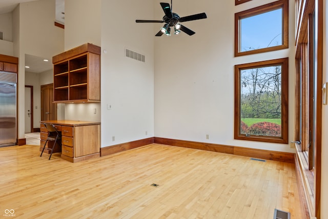 interior space featuring ceiling fan, light hardwood / wood-style floors, and a high ceiling