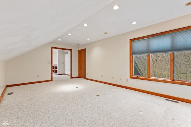 additional living space featuring light carpet and vaulted ceiling