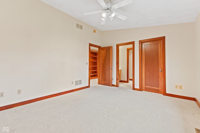 unfurnished bedroom with ceiling fan, light colored carpet, a spacious closet, and vaulted ceiling