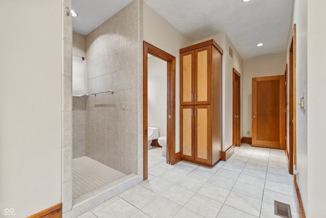 bathroom with tile patterned floors, toilet, and tiled shower