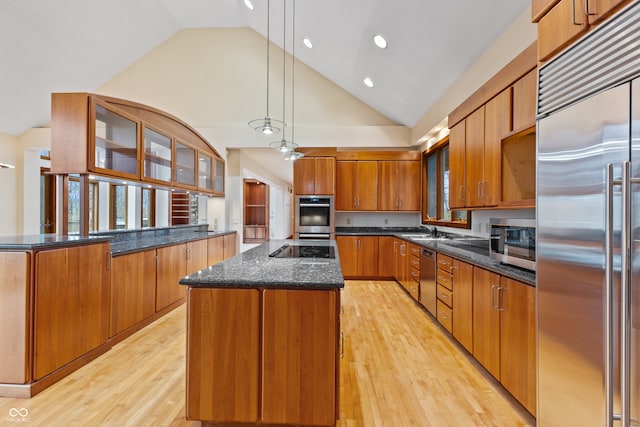 kitchen featuring a kitchen island, stainless steel appliances, decorative light fixtures, and light hardwood / wood-style floors