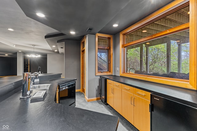 bar with sink, hanging light fixtures, and black dishwasher