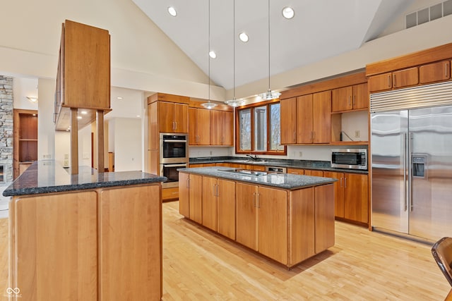 kitchen with a center island, high vaulted ceiling, light wood-type flooring, and appliances with stainless steel finishes