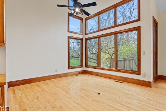 interior space featuring ceiling fan, light wood-type flooring, and a high ceiling