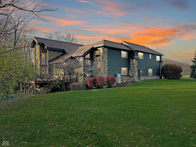 property exterior at dusk featuring a yard and a wooden deck