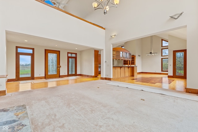 unfurnished living room featuring light hardwood / wood-style floors, high vaulted ceiling, and plenty of natural light