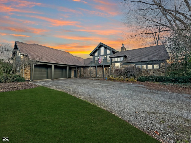 view of front of property featuring a garage, a balcony, and a yard