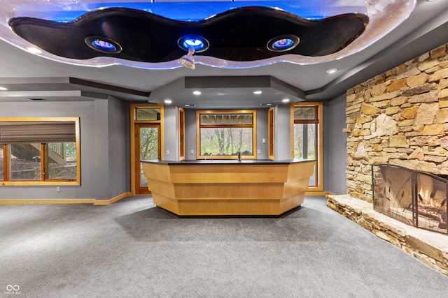 bar featuring carpet, plenty of natural light, and a stone fireplace