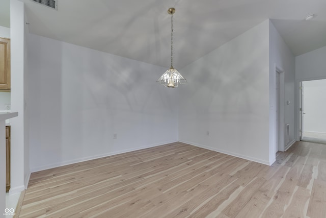 unfurnished dining area with a notable chandelier, light hardwood / wood-style floors, and vaulted ceiling