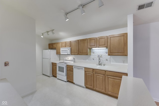 kitchen with rail lighting, decorative backsplash, white appliances, and sink