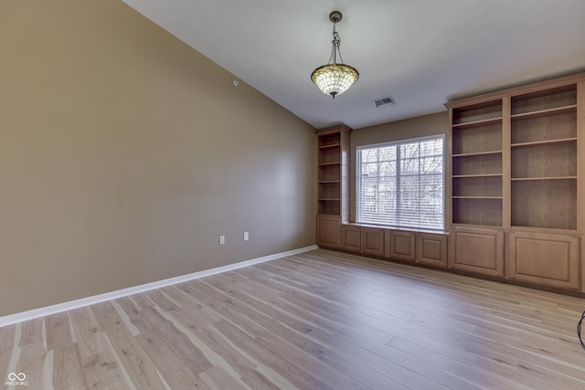 empty room featuring vaulted ceiling and light wood-type flooring