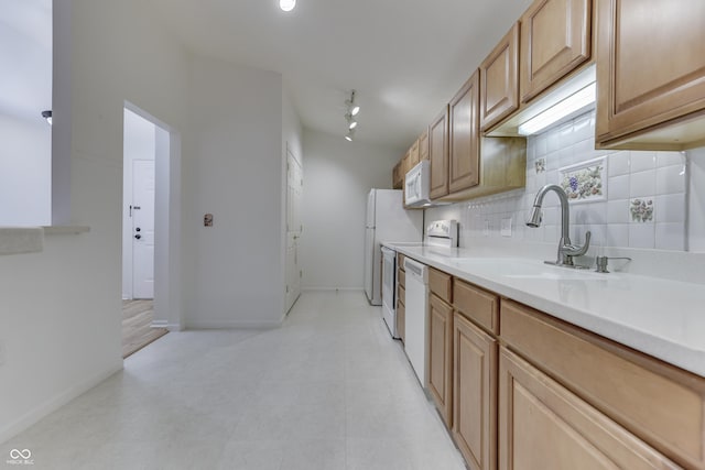 kitchen featuring white appliances, backsplash, and sink