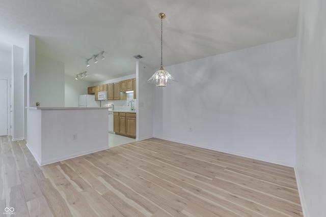 unfurnished living room featuring sink, track lighting, and light wood-type flooring