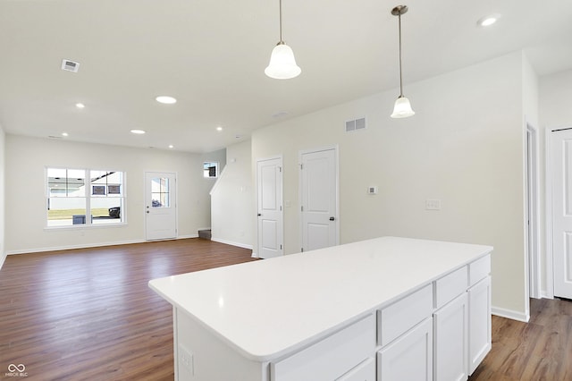 kitchen with pendant lighting, white cabinetry, a kitchen island, and dark wood-type flooring