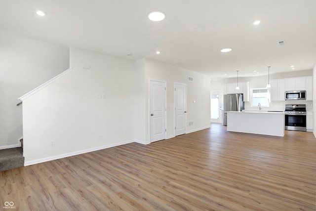 unfurnished living room with light wood-type flooring and sink