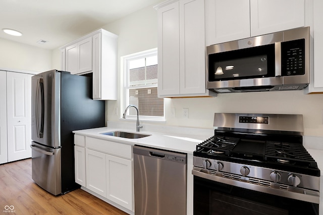 kitchen with white cabinetry, sink, light hardwood / wood-style floors, and appliances with stainless steel finishes