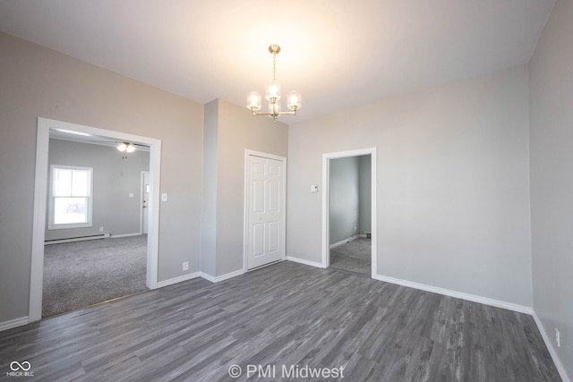 unfurnished room featuring dark hardwood / wood-style floors, baseboard heating, and a notable chandelier