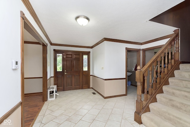 entrance foyer with crown molding, a textured ceiling, and light wood-type flooring